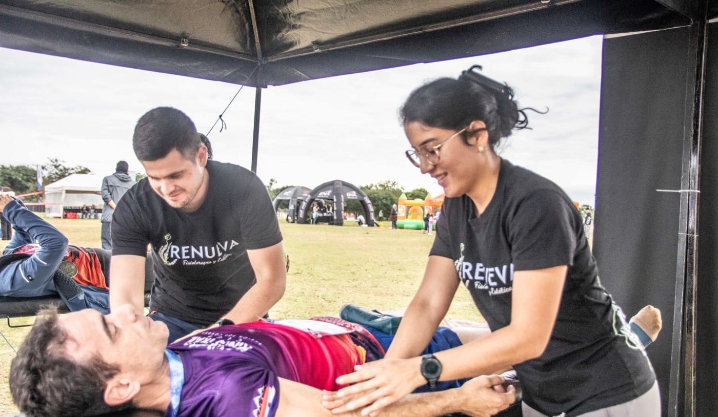 Dos fisioterapeutas de Renueva atendiendo a un corredor en una carpa